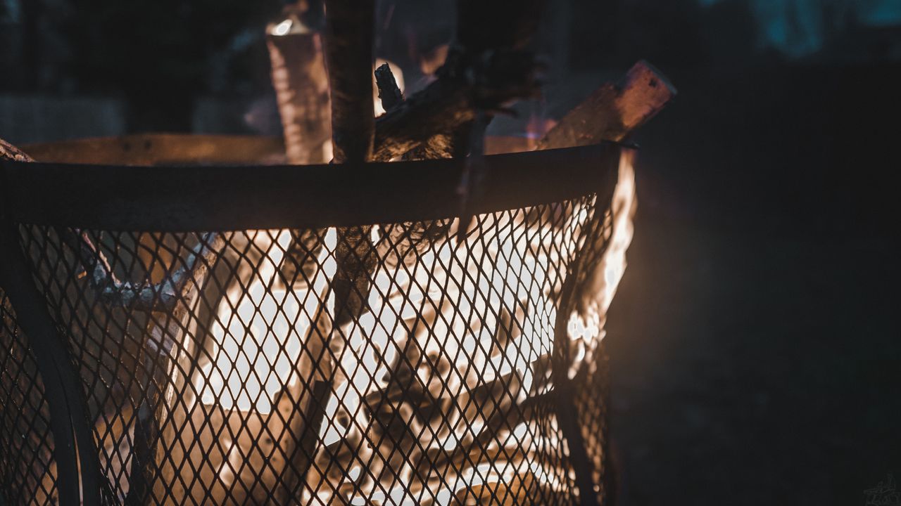 Outdoor corten steel fire pit with burning wood in a garden setting