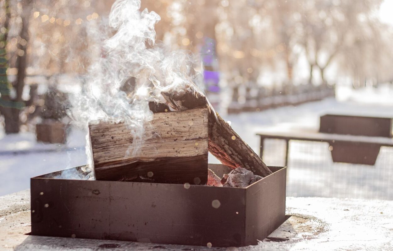 Outdoor corten steel fire pit with burning wood in a garden setting