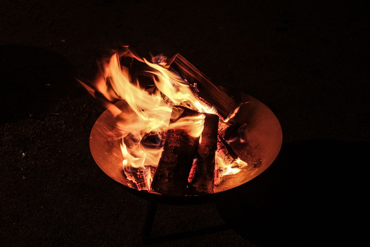 Outdoor corten steel fire pit with burning wood in a garden setting